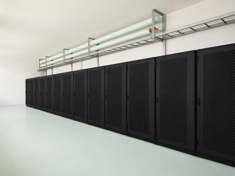 A row of closed racks in a quiet HPC machine room, with insulated cooling pipes overhead